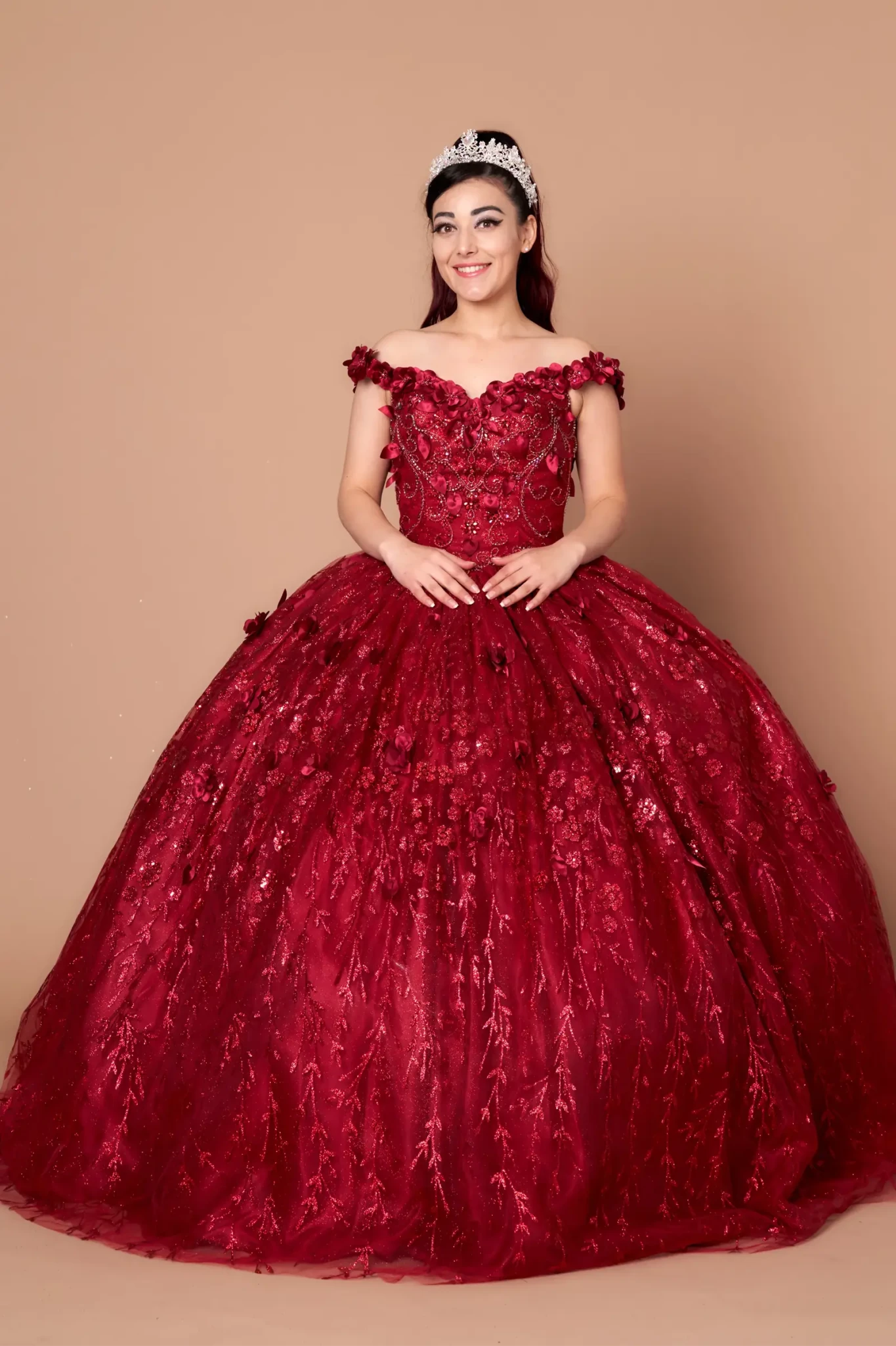 Front-Facing of a woman wearing Burgundy ball gown with off-shoulder neckline floral embellishments and full flowing skirt