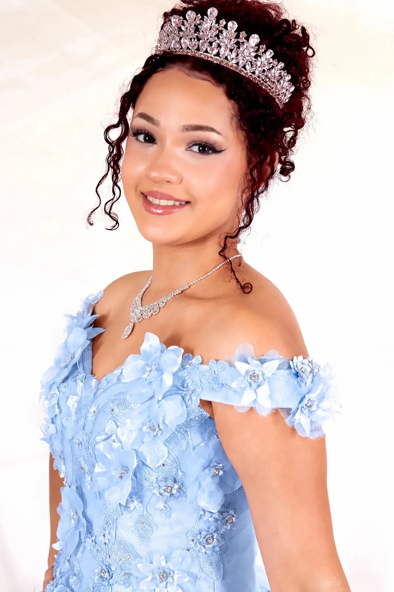 Woman wearing a light blue off-shoulder quinceanera dress with floral details