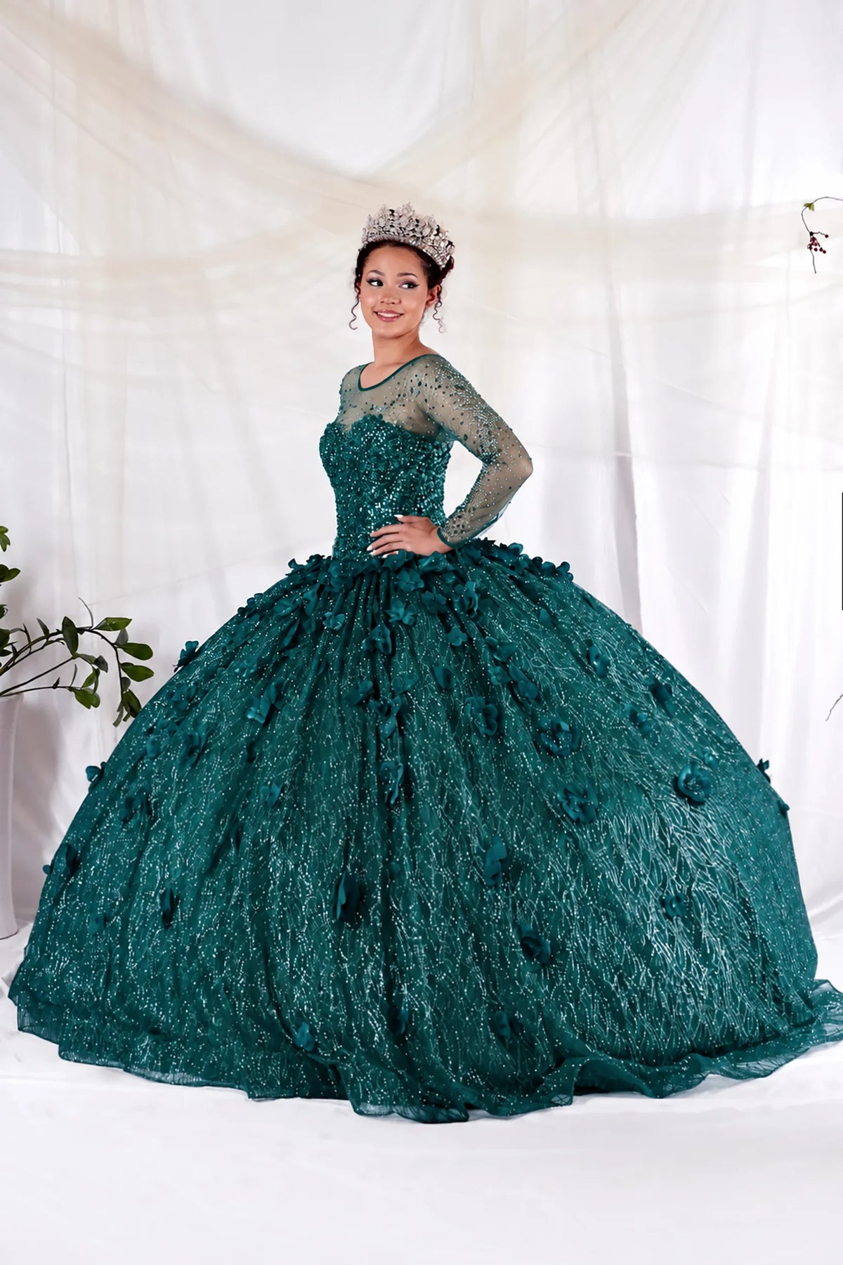 Emerald Green quinceañera dress showcases sheer embellished long sleeves above textured lace ball gown skirt.
