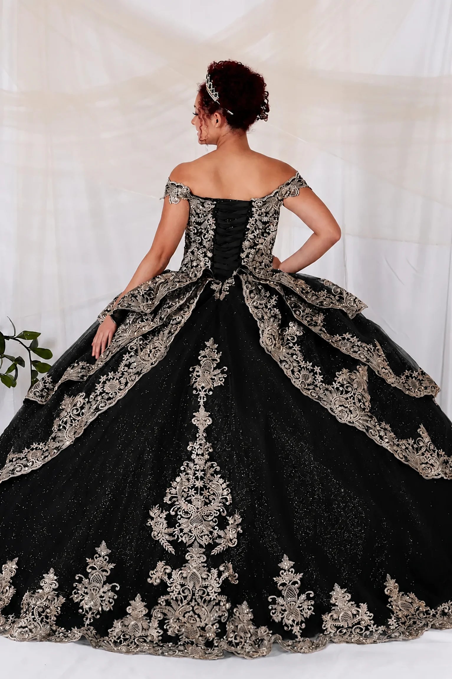 off-the-shoulder ball gown in black showing tulle skirt with elaborate floral lace appliques and a matching lace-trimmed overskirt