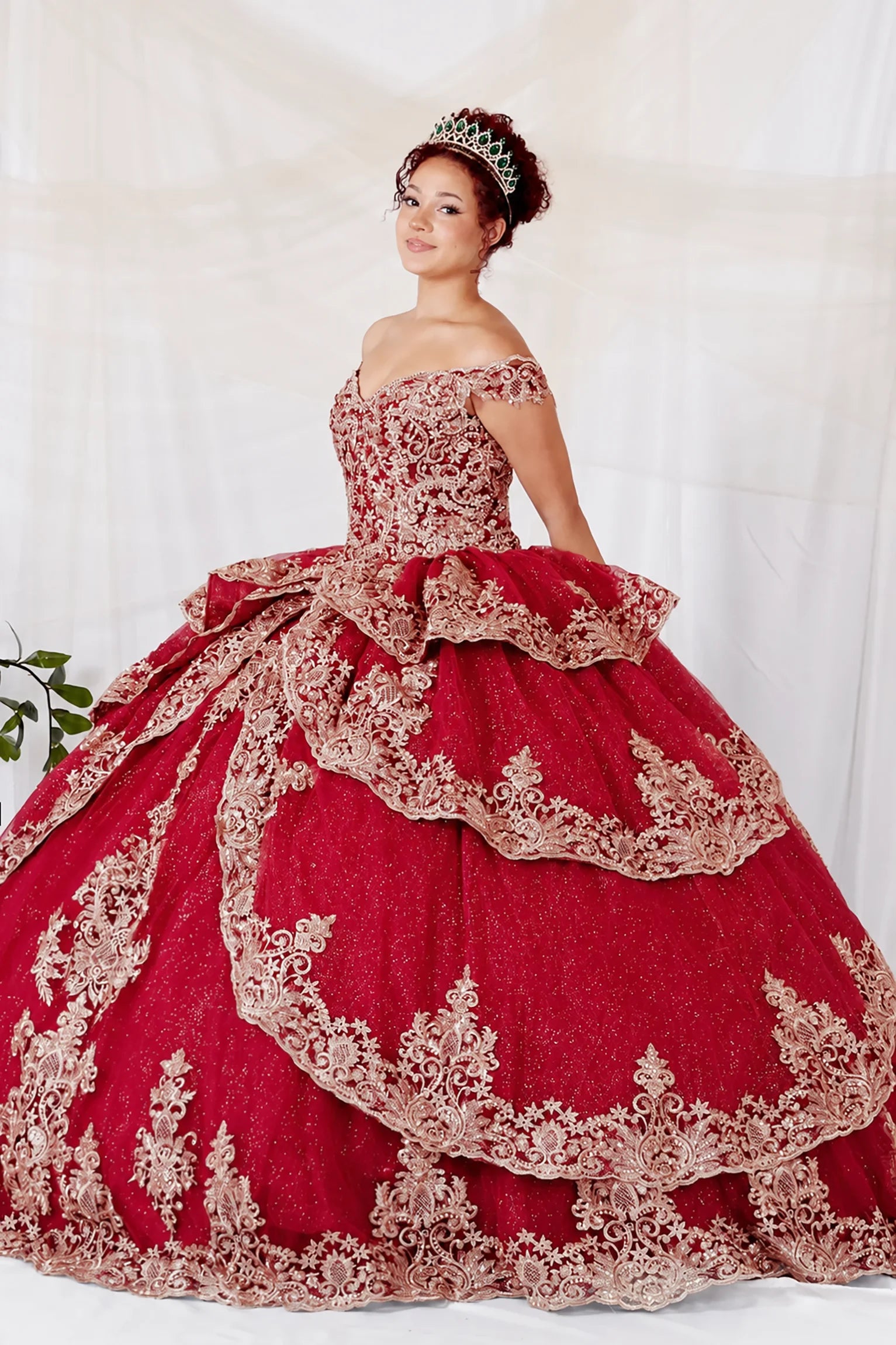 off-the-shoulder burgundy quinceañera dress with extensive gold lace embroidery and a large ruffled skirt