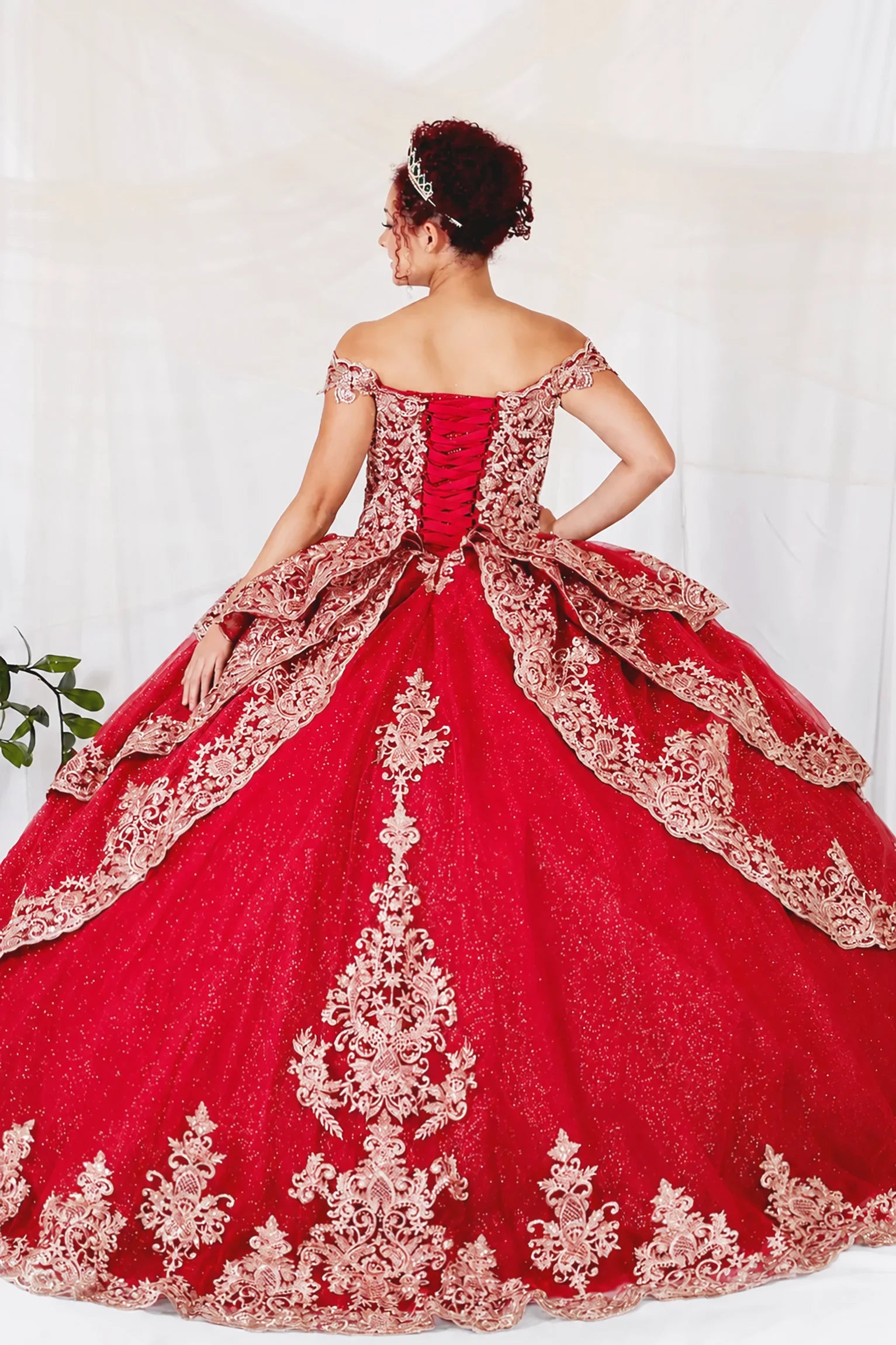 A red off-the-shoulder quinceañera ball gown with intricate gold lace embroidery