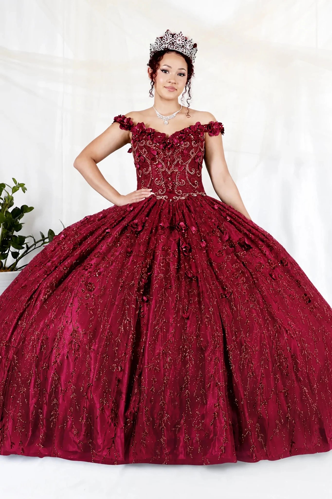 Burgundy quinceañera ball gown with off‑shoulder neckline, delicate floral applique and flowing skirt