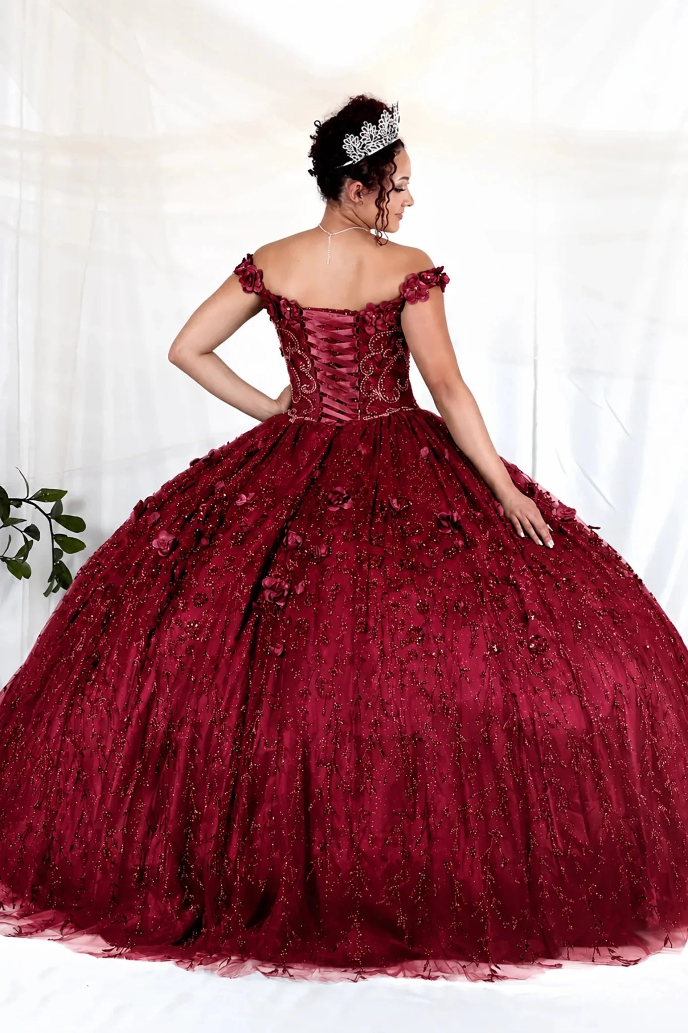 Burgundy quinceañera ball gown with off‑shoulder neckline, delicate floral applique and flowing skirt