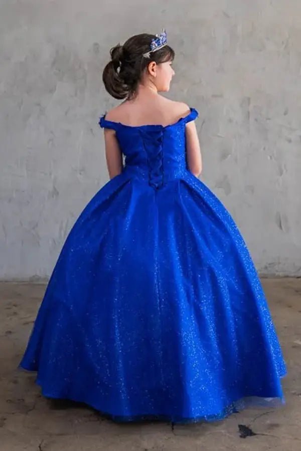 Kid standing back-facing in red ball gown with lace-up closure, 3D floral appliqué accents, glitter tulle, and cascading full-length skirt