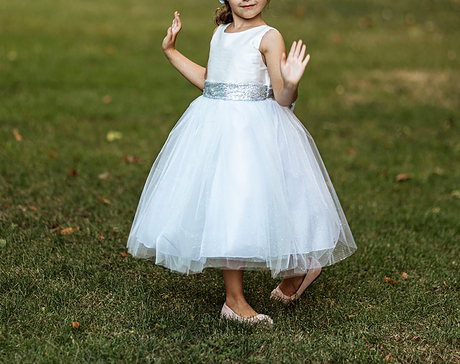 Silver / White USA Made | Sequin V-Back Tulle Flower Girl Dress with detachable Ribbon pin - front view of girl wearing dress walking on grass