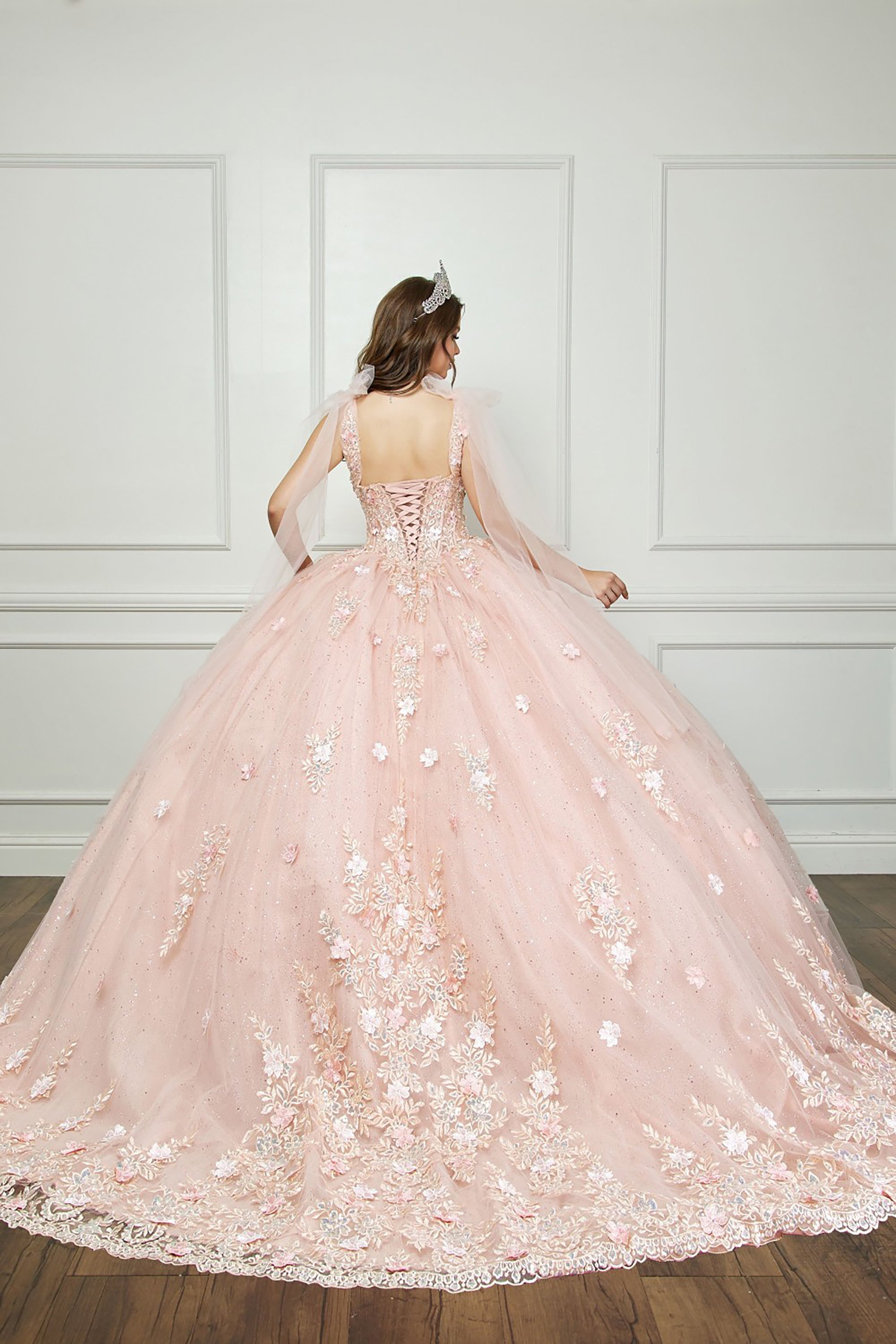 Quinceanera | Blush-Peach Flower Embroidery, Gem Detailing, and glitter lining Quince Ballgown with Tulle Shoulder Drape - back view of woman wearing dress